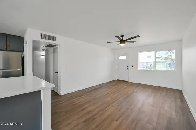 an empty room with wooden floor and a ceiling fan