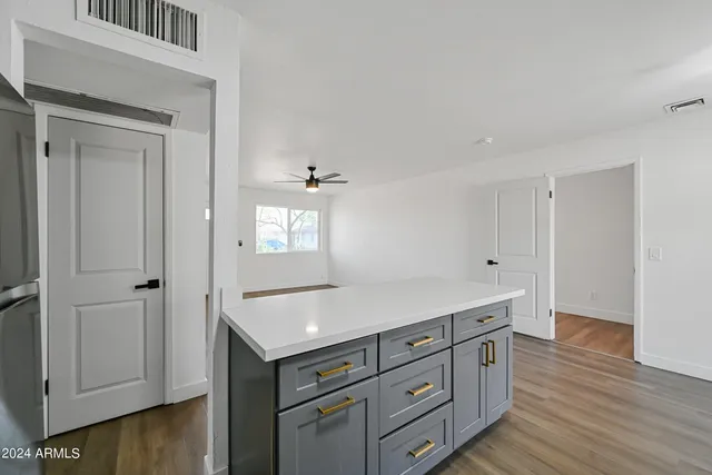 a kitchen with white cabinets and wooden floor