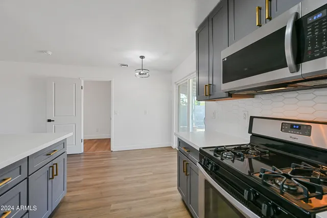a kitchen with stainless steel appliances and wooden floor