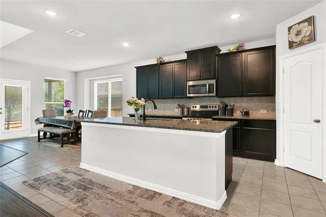 a kitchen with granite countertop a refrigerator and a stove top oven