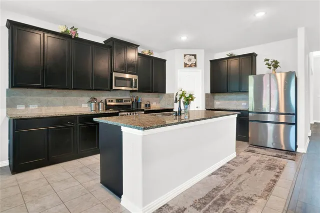 a kitchen with granite countertop a refrigerator and a stove top oven