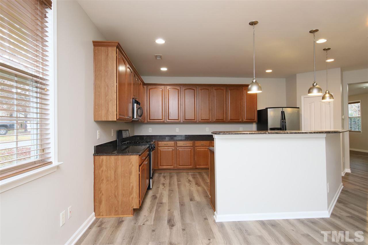 175 Solheim Lane Raleigh, NC 27603 - Photo 8 of 26 a kitchen with kitchen island a sink wooden floor and a large window