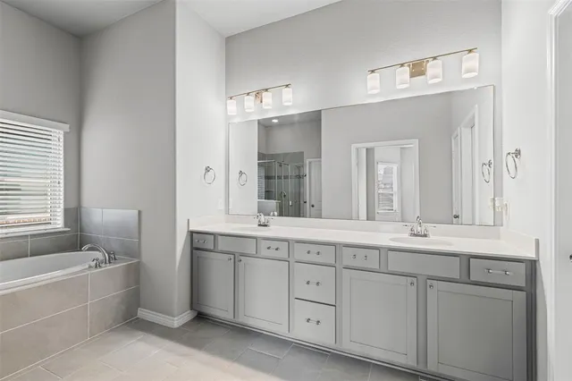 a bathroom with a granite countertop double vanity sink a mirror and a bathtub