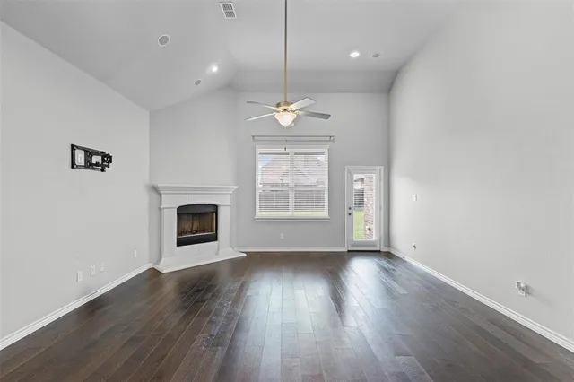 a view of an empty room with wooden floor fireplace and a window