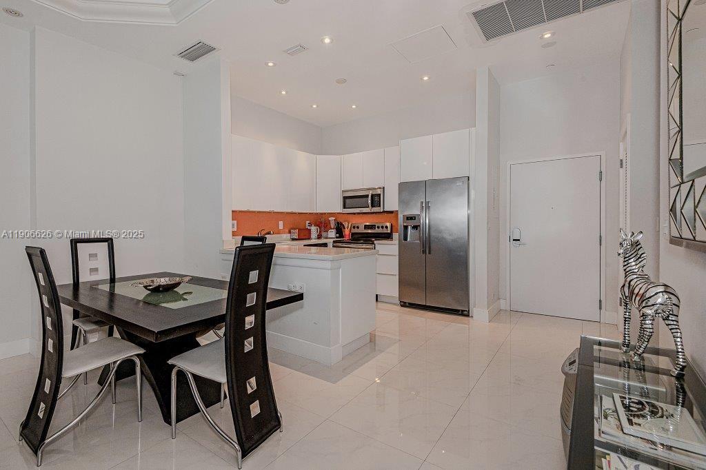 2301 Collins Avenue, Unit 1619 Miami Beach, FL 33139 - Photo 12 of 28 a kitchen with stainless steel appliances kitchen island granite countertop a table chairs and a refrigerator