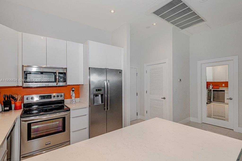 2301 Collins Avenue, Unit 1619 Miami Beach, FL 33139 - Photo 14 of 28 a kitchen with stainless steel appliances a refrigerator a stove and white cabinets