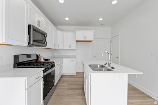 1262 West 500 South Logan, UT 84321 - Photo 10 of 39 Modern kitchen featuring white cabinetry, light-toned wood-finish flooring, a stainless steel gas range, microwave, and a double basin sink with a gooseneck faucet