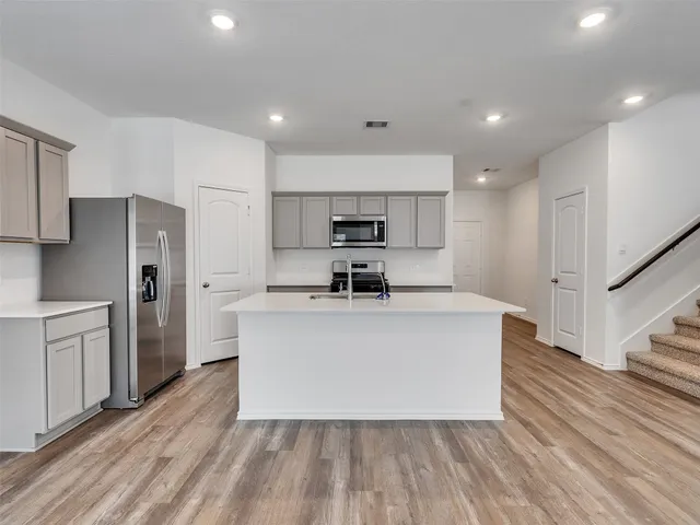 a white kitchen with wooden floors stainless steel appliances