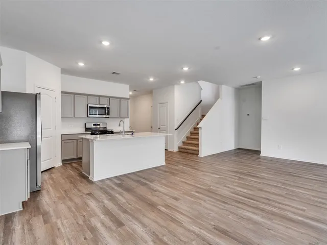 a view of kitchen with cabinets stainless steel appliances and wooden floor