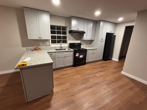 a kitchen with granite countertop a refrigerator stove top oven and cabinets