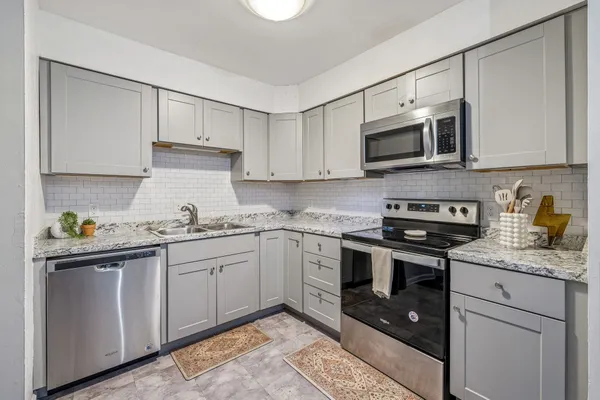 a kitchen with stainless steel appliances granite countertop a sink a stove a microwave and cabinets