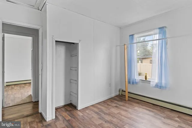 an empty room with wooden floor mirror and windows