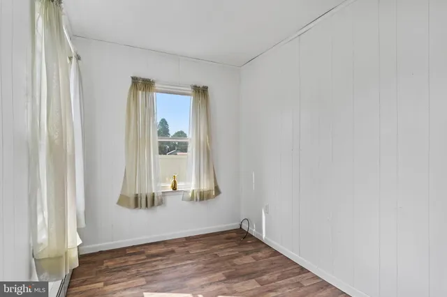 an empty room with wooden floor cabinet and windows