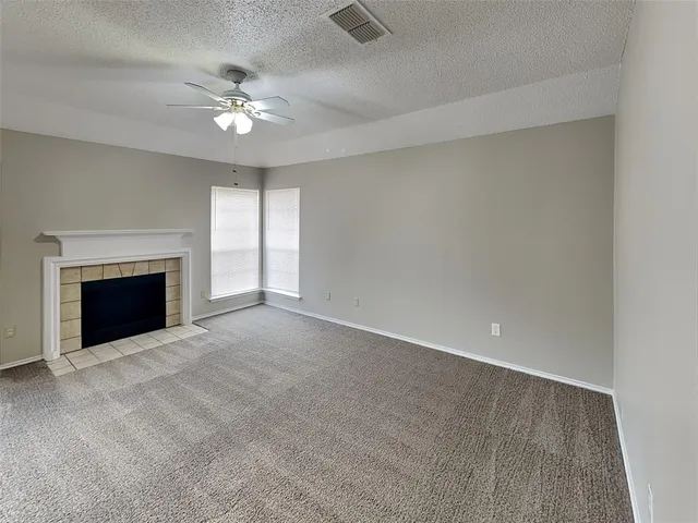 a view of an empty room with chandelier fan and fire place
