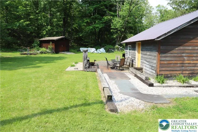 a view of a house with a yard and large trees