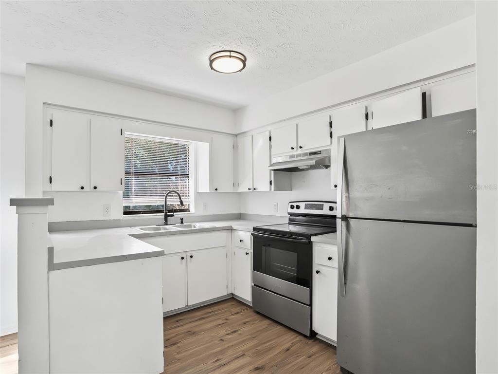 5911 Northwest 9th Street Ocala, FL 34482 - Photo 11 of 37 a kitchen with stainless steel appliances granite countertop white refrigerator stove a sink and dishwasher with wooden floor