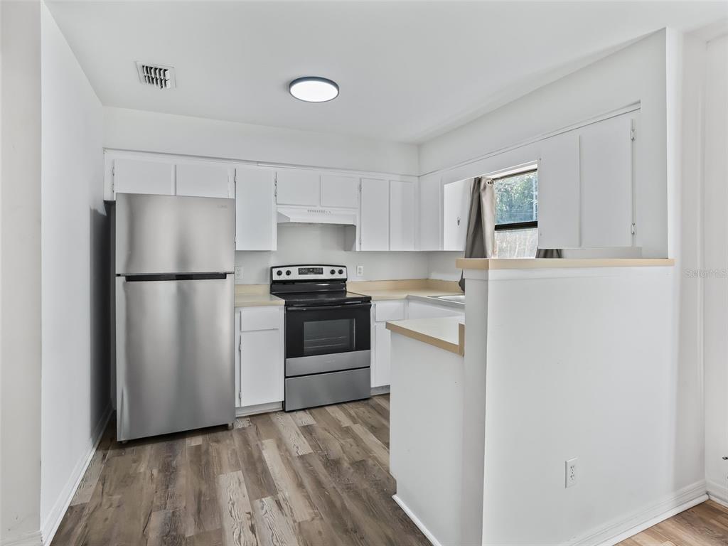 5911 Northwest 9th Street Ocala, FL 34482 - Photo 26 of 37 a kitchen with a refrigerator a stove top oven and white cabinets