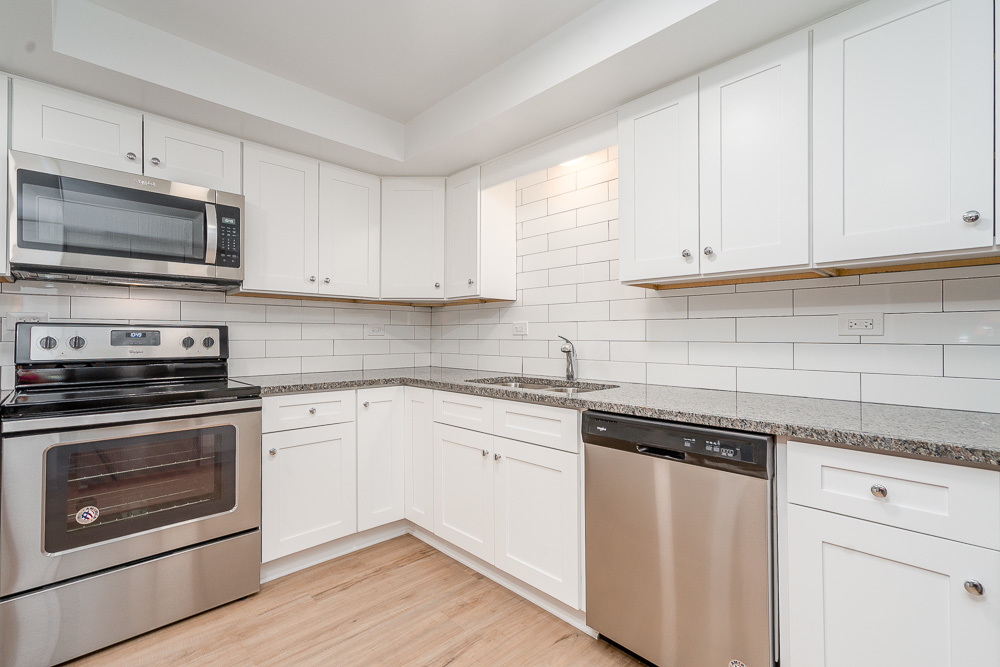 21 South Waiola Avenue, Unit 7 La Grange, IL 60525 - Photo 5 of 18 a kitchen with granite countertop white cabinets and stainless steel appliances