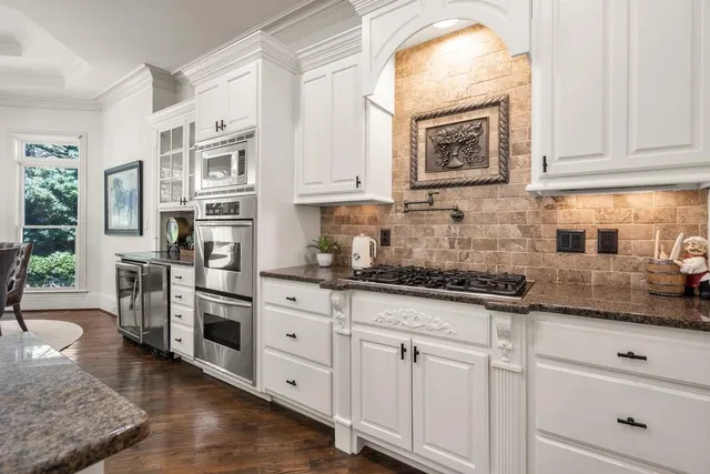 a kitchen with stainless steel appliances granite countertop a stove a sink and white cabinets