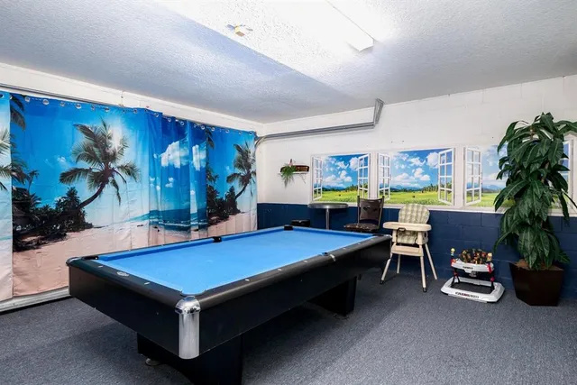 a room with furniture pool table table and paintings on the wall