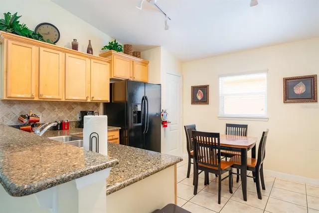 a kitchen with stainless steel appliances granite countertop a table chairs and a refrigerator