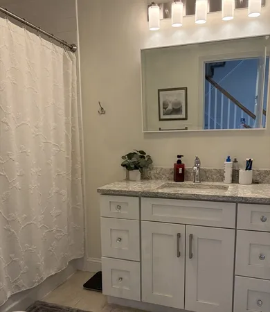 a bathroom with a granite countertop sink a mirror and shower