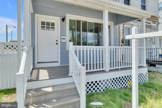 a porch with a bench next to a yard