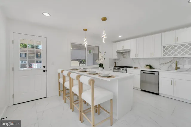 a kitchen that has a lot of white cabinets and stainless steel appliances