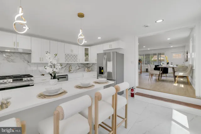 a kitchen with stainless steel appliances granite countertop a dining table chairs stove refrigerator and cabinets