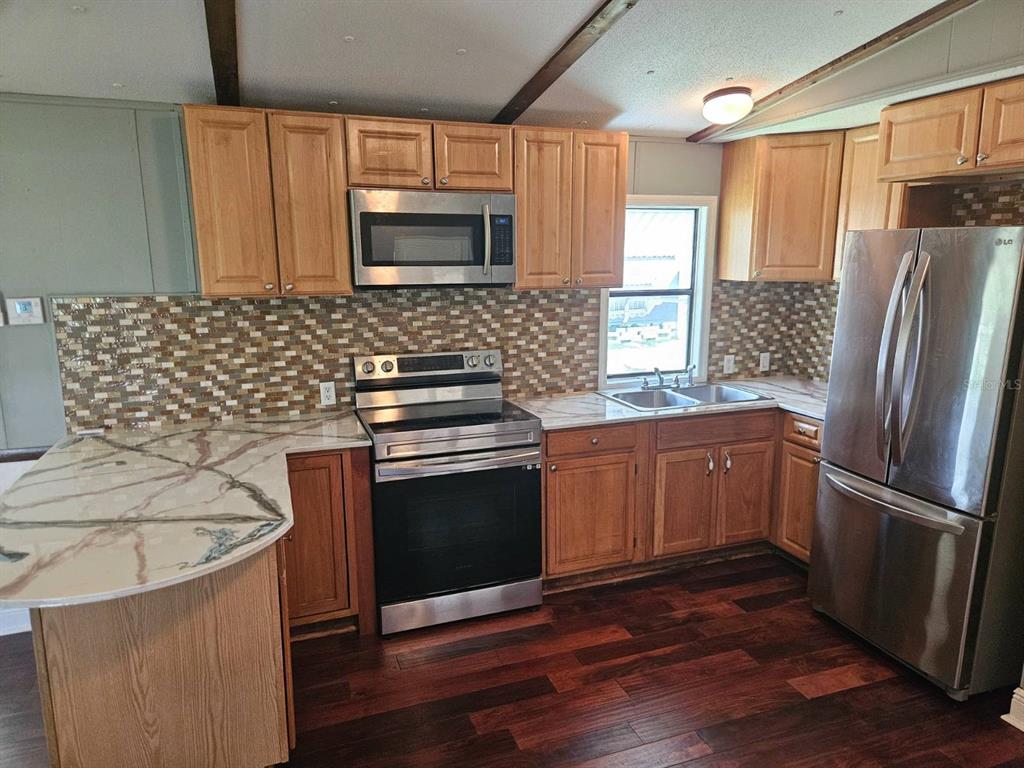 6445 Belle Terre Road New Port Richey, FL 34653 - Photo 8 of 16 a kitchen with granite countertop a refrigerator stove and microwave