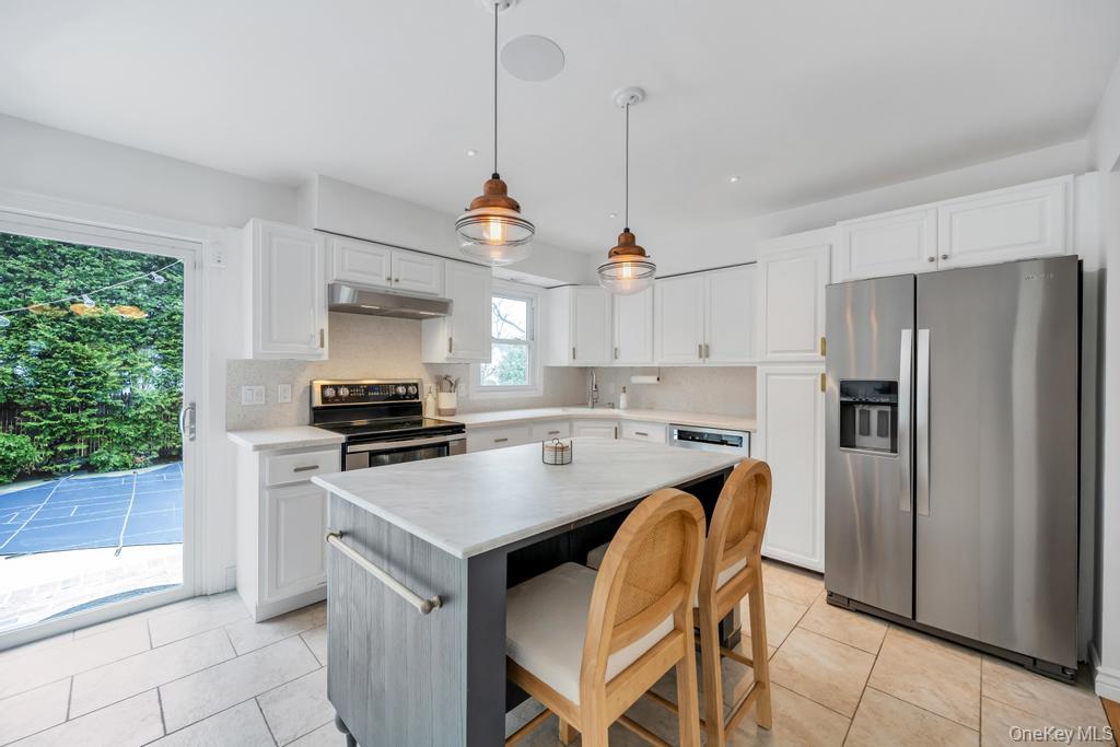 8 Lovell Road Hampton Bays, NY 11946 - Photo 11 of 20 a kitchen with stainless steel appliances granite countertop a stove a refrigerator a sink a stove and white cabinets with wooden floor