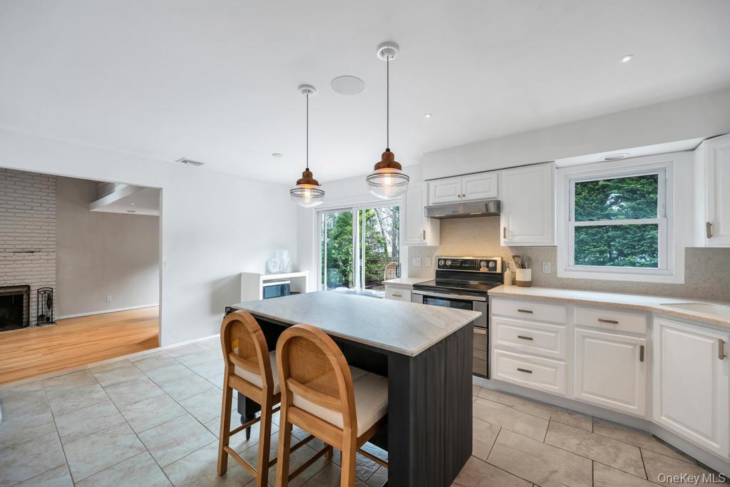 8 Lovell Road Hampton Bays, NY 11946 - Photo 12 of 20 a kitchen that has a stove a sink a microwave oven a dining table and chairs with wooden floor