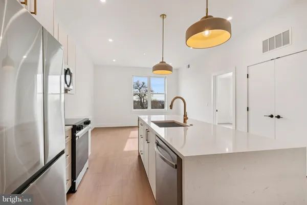 a large kitchen with cabinets a sink and a stove top oven with wooden floor