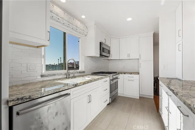 a kitchen with granite countertop white cabinets and white appliances
