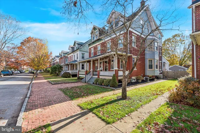a view of a white house with a yard and table and chairs under an umbrella