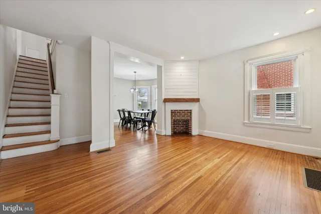 an empty room with wooden floor fireplace and windows