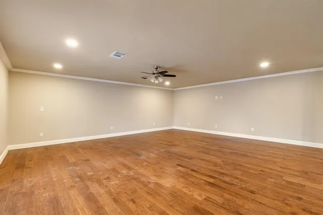 an empty room with wooden floor and fan