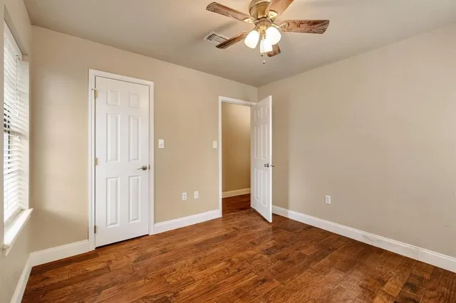 an empty room with wooden floor closet and windows