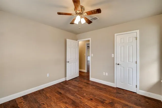 an empty room with wooden floor and ceiling fan