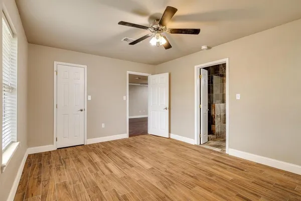 a view of empty room with wooden floor and fan