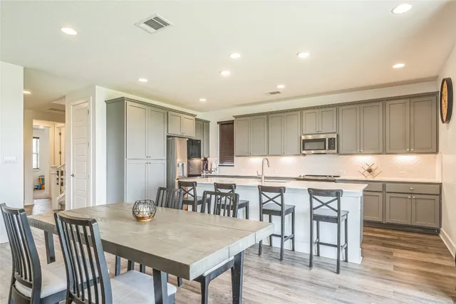 a kitchen with stainless steel appliances granite countertop a dining table chairs and white cabinets