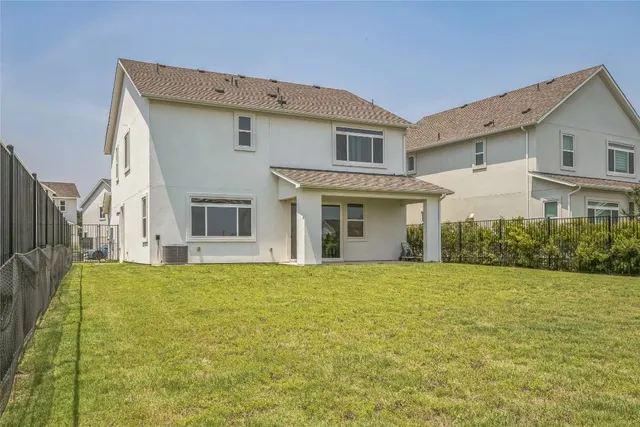 a view of a white house next to a yard with potted plants