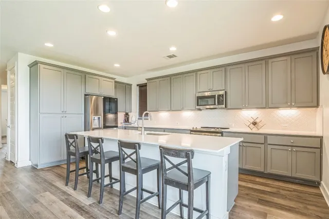 a kitchen with stainless steel appliances granite countertop a table and chairs in it