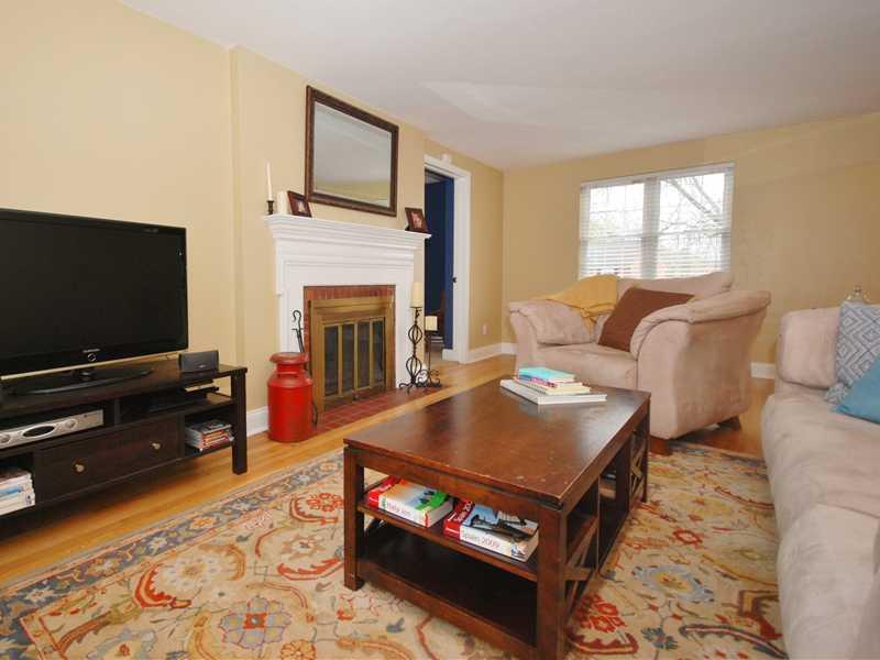 Living Room. Neutral wall tones with contrasting wooden trim, plentiful natural light, and a wood-burning fireplace are elements of the spacious living room.