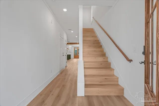 a view of staircase with wooden floor and white walls