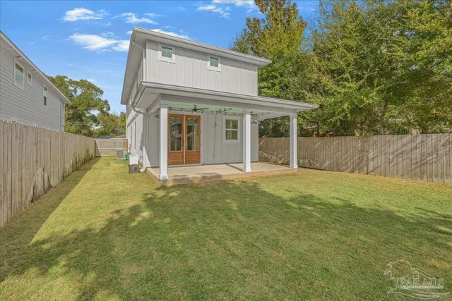 a view of a white house with a large tree and wooden fence