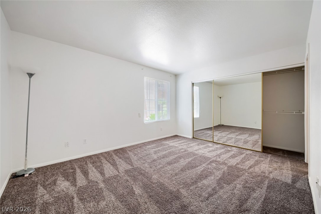 9325 West Desert Inn Road, Unit 177 Las Vegas, NV 89117 - Photo 17 of 24 A well-lit bedroom with plush carpeting and expansive mirrored closet doors.