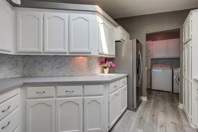 a kitchen with white cabinets and refrigerator