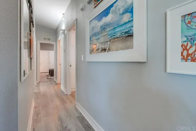 a view of a hallway with wooden floor and a painting on the wall