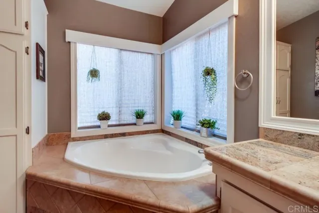 a bathroom with a granite countertop sink and a bathtub